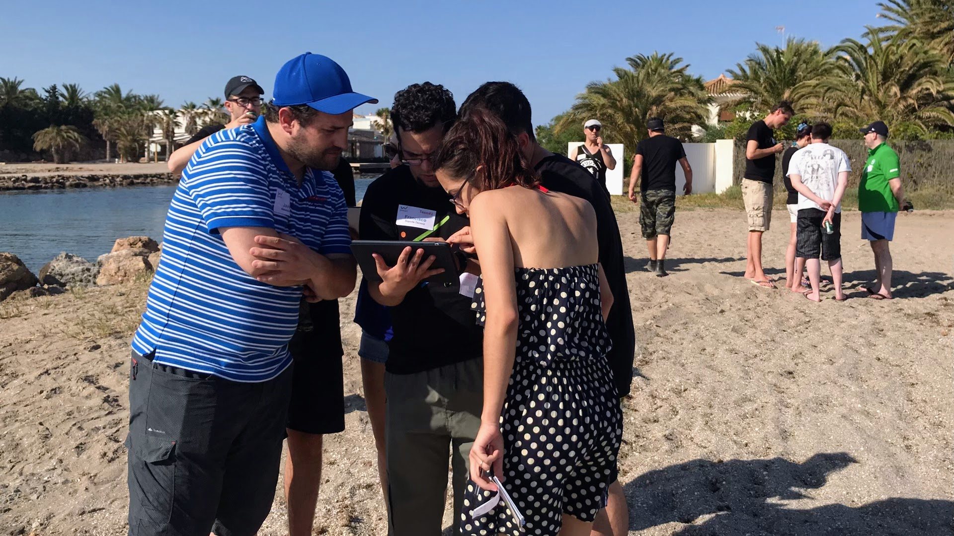 Equipo de empresa resolviendo un reto con tablet en una gymkana digital en la playa